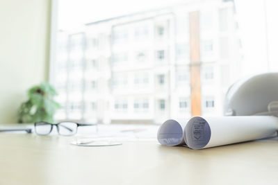 Rolled papers and eyeglasses on table at office