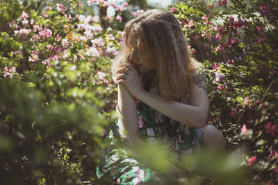 Absorbed in thought girl surrounded by shrubs with pink flowers scenic photography
