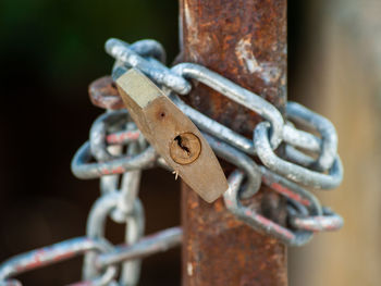 Close-up of rusty chain tied up on metal gate