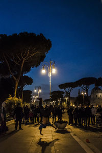 People at illuminated city against sky at night