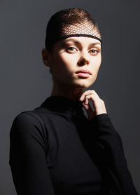 Portrait of young woman against black background