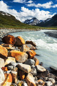 Scenic view of lake by rocks against sky, jotunheimen, norway