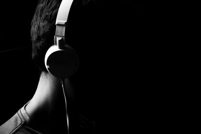 Side view of man wearing headphones against black background