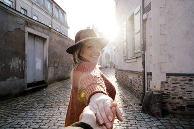 Portrait of woman holding hand in alley