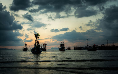 Many fishing boat in the sea when low tide under cloudy sky in the evening