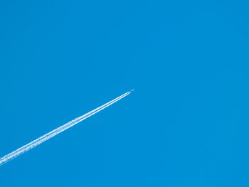 Low angle view of vapor trail against clear blue sky