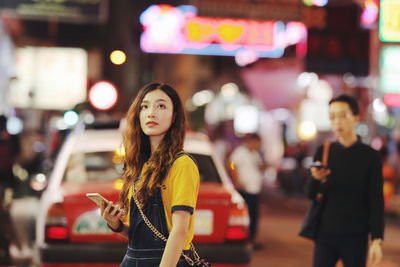 Woman standing on illuminated city street