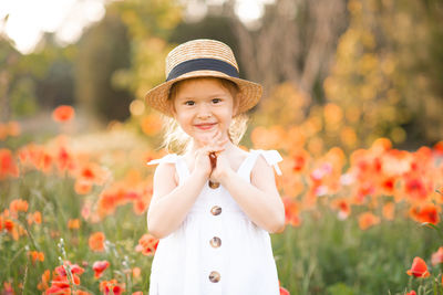 Portrait of cheerful girl wearing hat on flowering field