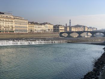 Arch bridge over river against sky in city