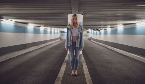 Portrait of serious woman standing under illuminated tunnel