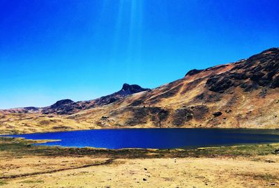 Scenic view of lake and mountains against clear blue sky