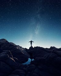 Low angle view of man standing on mountain against sky at night