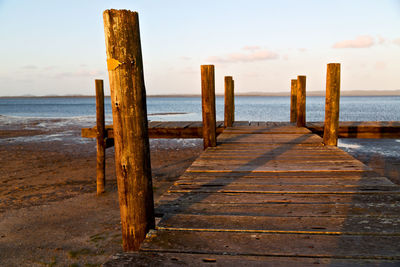 Wooden pier on beach against sky