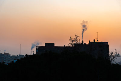 Smoke emitting from chimney against sky at sunset