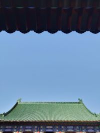 Low angle view of building roof against clear blue sky