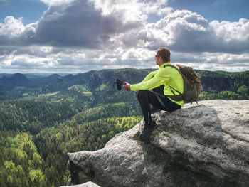 Rear view of backpacker sit on edge. end of foot path in a rocky landscape. hiking or climbing.