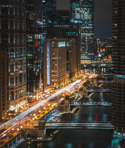 Illuminated bridge by buildings in city at night