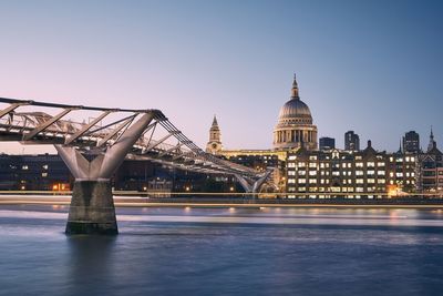 Illuminated bridge over river with city in background