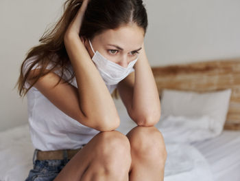 Midsection of woman sitting on bed at home