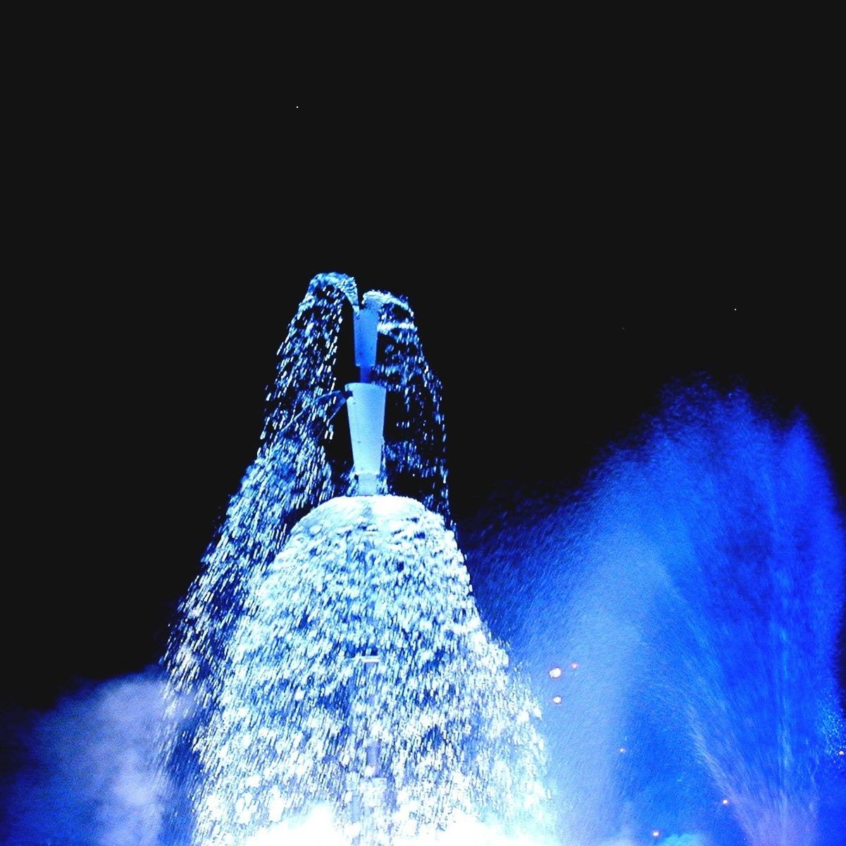 blue, illuminated, low angle view, copy space, night, lighting equipment, clear sky, glowing, winter, outdoors, cold temperature, water, light - natural phenomenon, sky, snow, no people, built structure, purple, fountain, nature