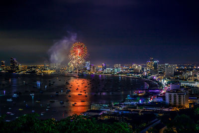 Firework display over illuminated buildings in city at night