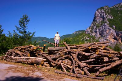 Rear view of man standing on rock against blue sky