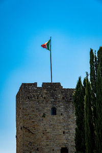 Low angle view of flag on building against clear blue sky