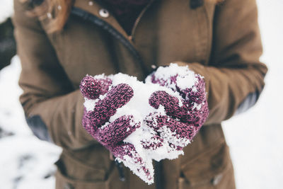 Close-up of female hands holding snow