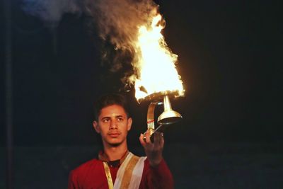Portrait of young man standing against fire