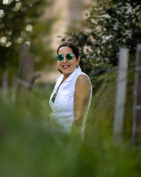 Portrait of young woman standing against trees