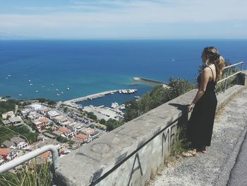 Rear view of woman standing by sea against sky