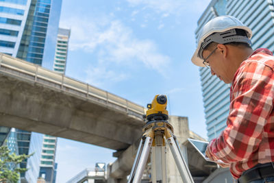 Low angle view of man looking at construction site against sky