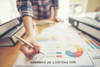 Midsection of businesswoman writing on document at desk