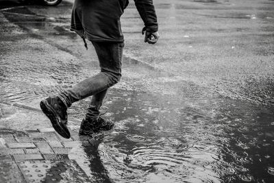 Low section of man running on wet road