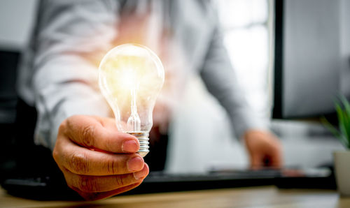 Close-up of hand holding light bulb