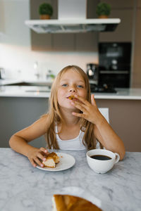Portrait of young woman having food at home