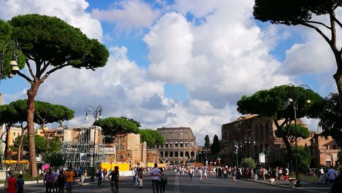 People at town square against cloudy sky