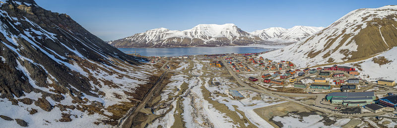 Scenic view of townscape by snowcapped mountains against sky