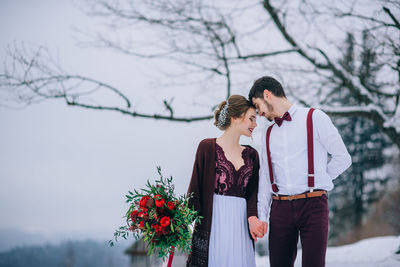 Young couple standing on tree against plants