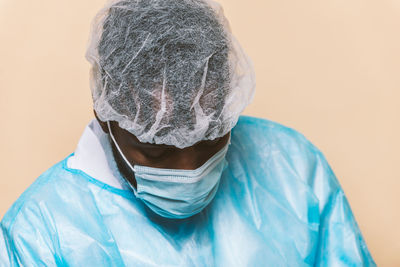 Doctor wearing mask sitting against colored background