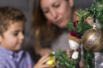 Mother and son decorating christmas tree at home