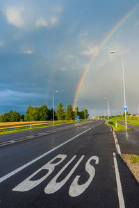 Rainbow over road against sky