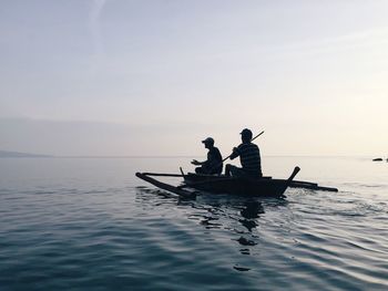 Men in boat on sea against sky