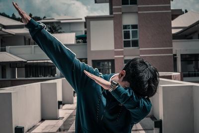 Side view of man holding umbrella against building in city