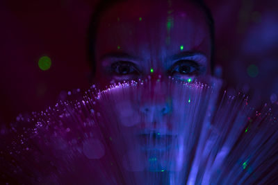 Portrait of beautiful young woman against illuminated background