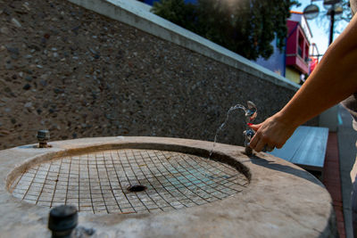 Cropped image of woman spinning drinking fountain tap