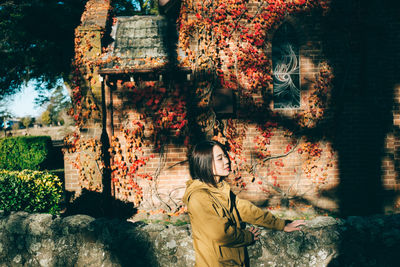 Side view of woman standing by building