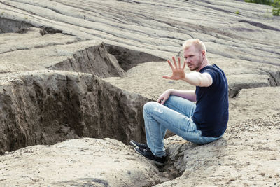 Side view of man sitting on rock