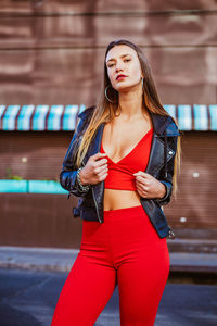 Beautiful young woman standing against red wall