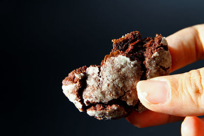 Close-up of hand holding ice cream against black background